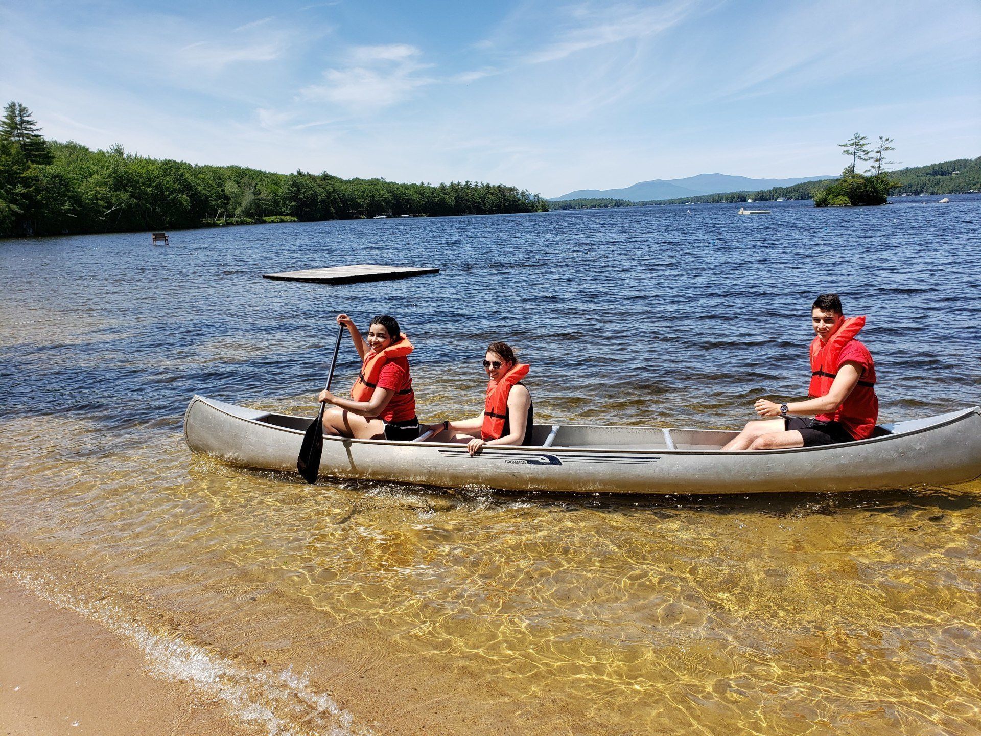 Three people are in a canoe on a lake.