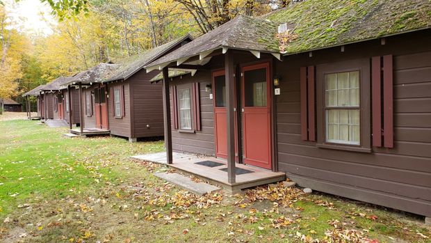 A row of cabins with red doors and windows are lined up in a field.