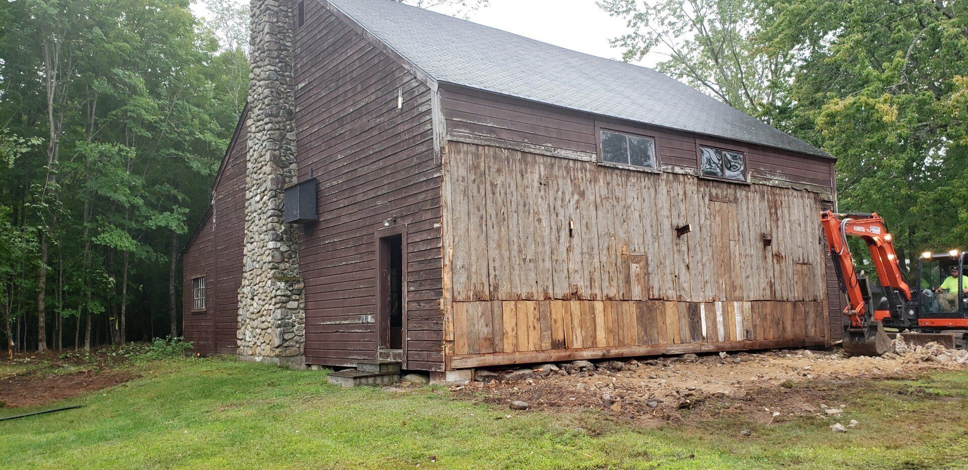 A large brick building is being demolished by a bulldozer.
