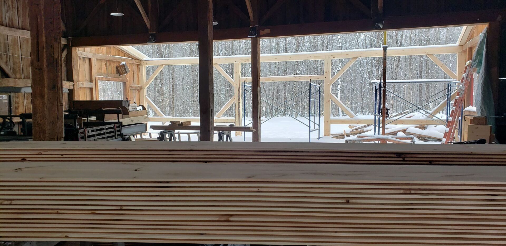 A large stack of wood is sitting inside of a building.