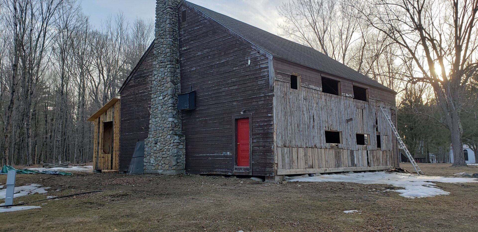 A large house with a red door is sitting in the middle of a field.