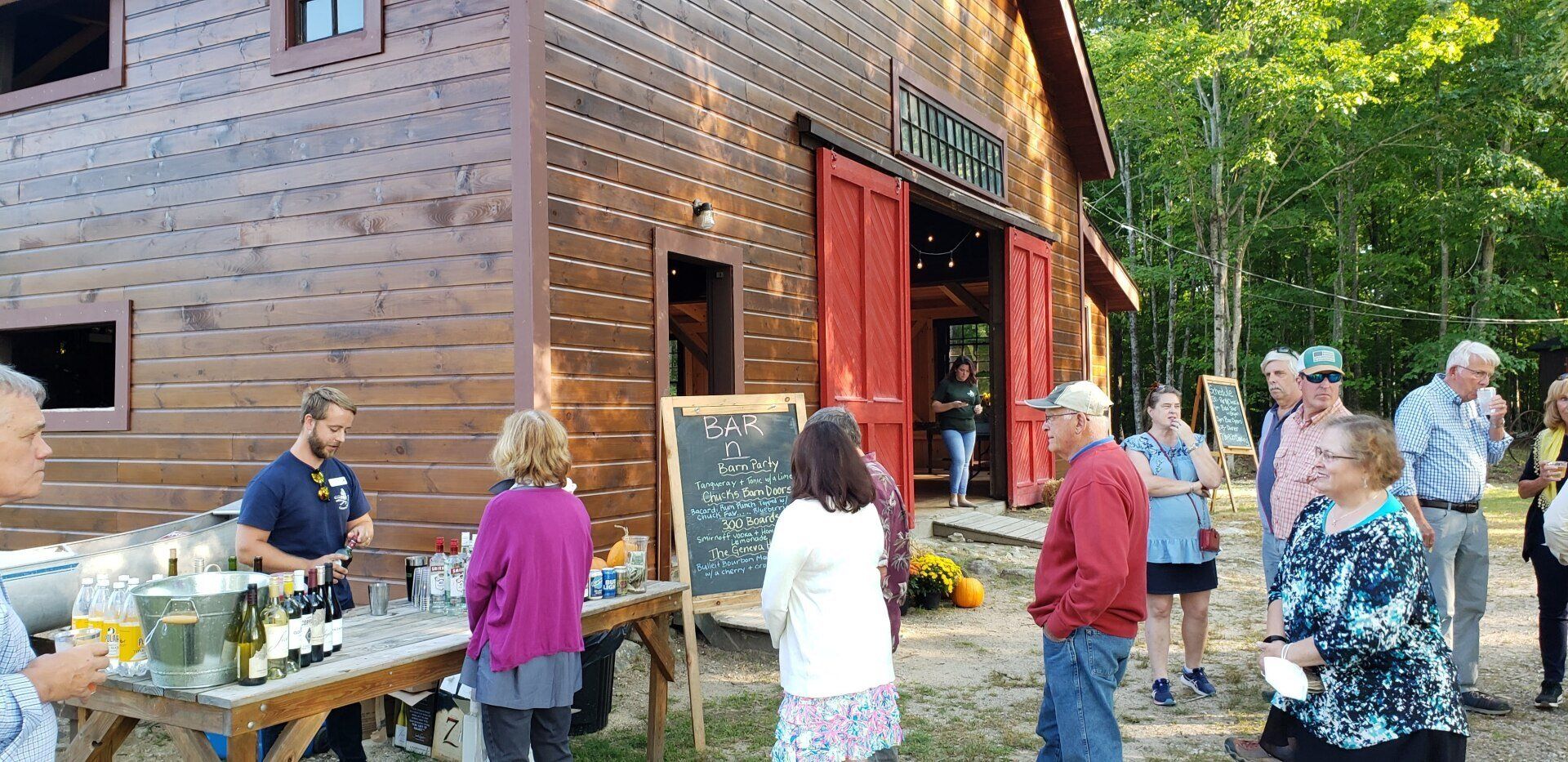 A group of people are standing in front of a wooden barn.