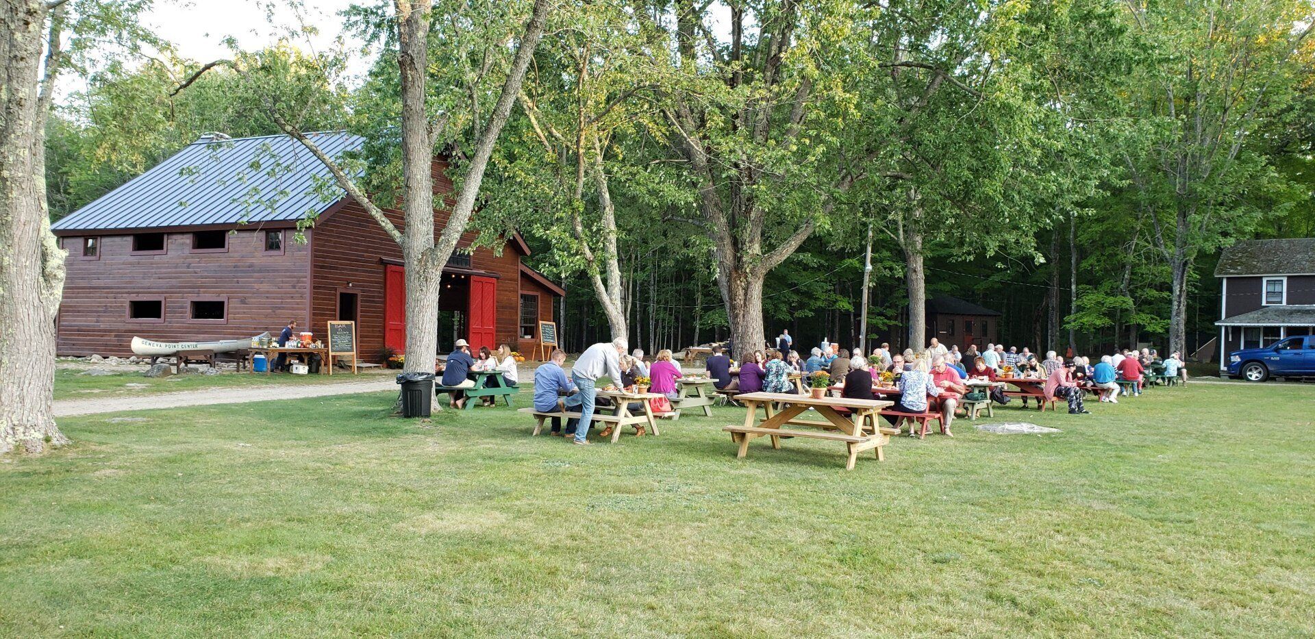 A group of people are sitting at picnic tables in a park.