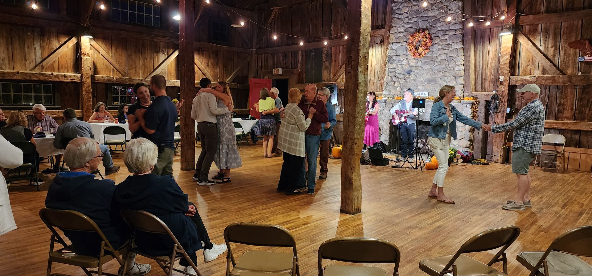 A group of people are dancing in a barn.