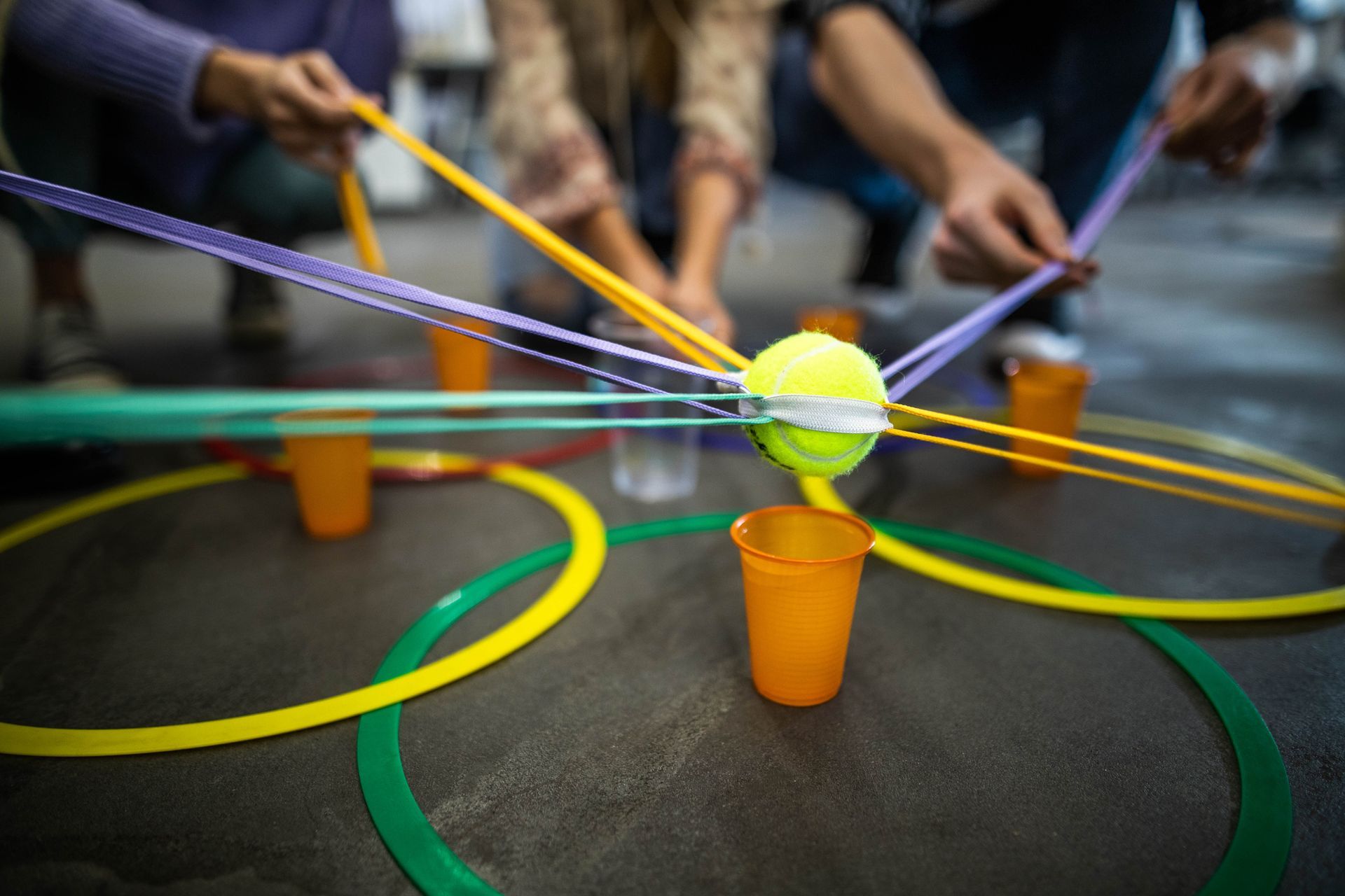 A group of people are playing a game with ropes and cups.