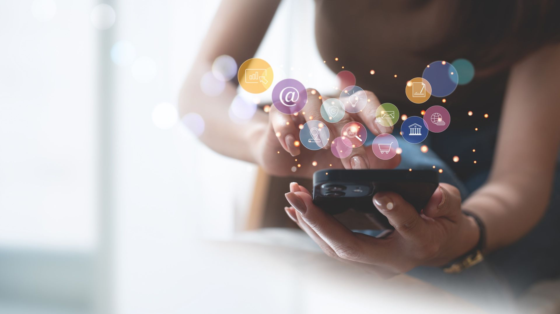 A woman is holding a cell phone in her hands with icons coming out of it.