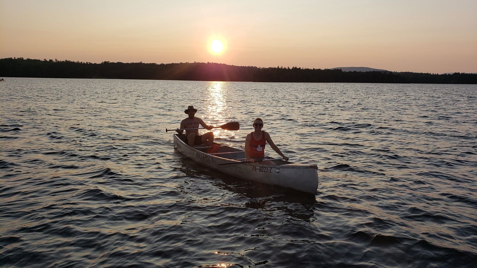 Two people in a canoe on a lake at sunset