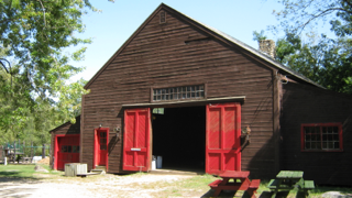 A barn with red doors and a picnic table in front of it