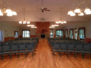 A large room with rows of chairs and a fireplace