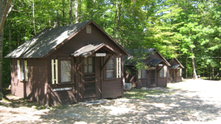 A row of small cabins in the middle of a forest.