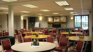 A large room with tables and chairs and a fireplace