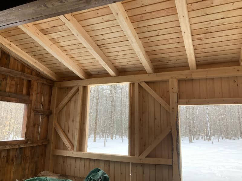 The inside of a wooden building with a snowy forest in the background