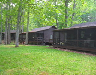 A row of cabins with screened in porches in the woods.