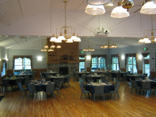 A large room with tables and chairs and a fireplace