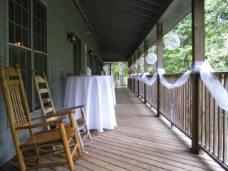A wooden porch with rocking chairs and tables