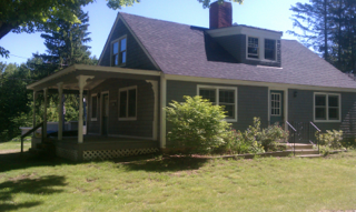 A house with a porch and a chimney on top of it
