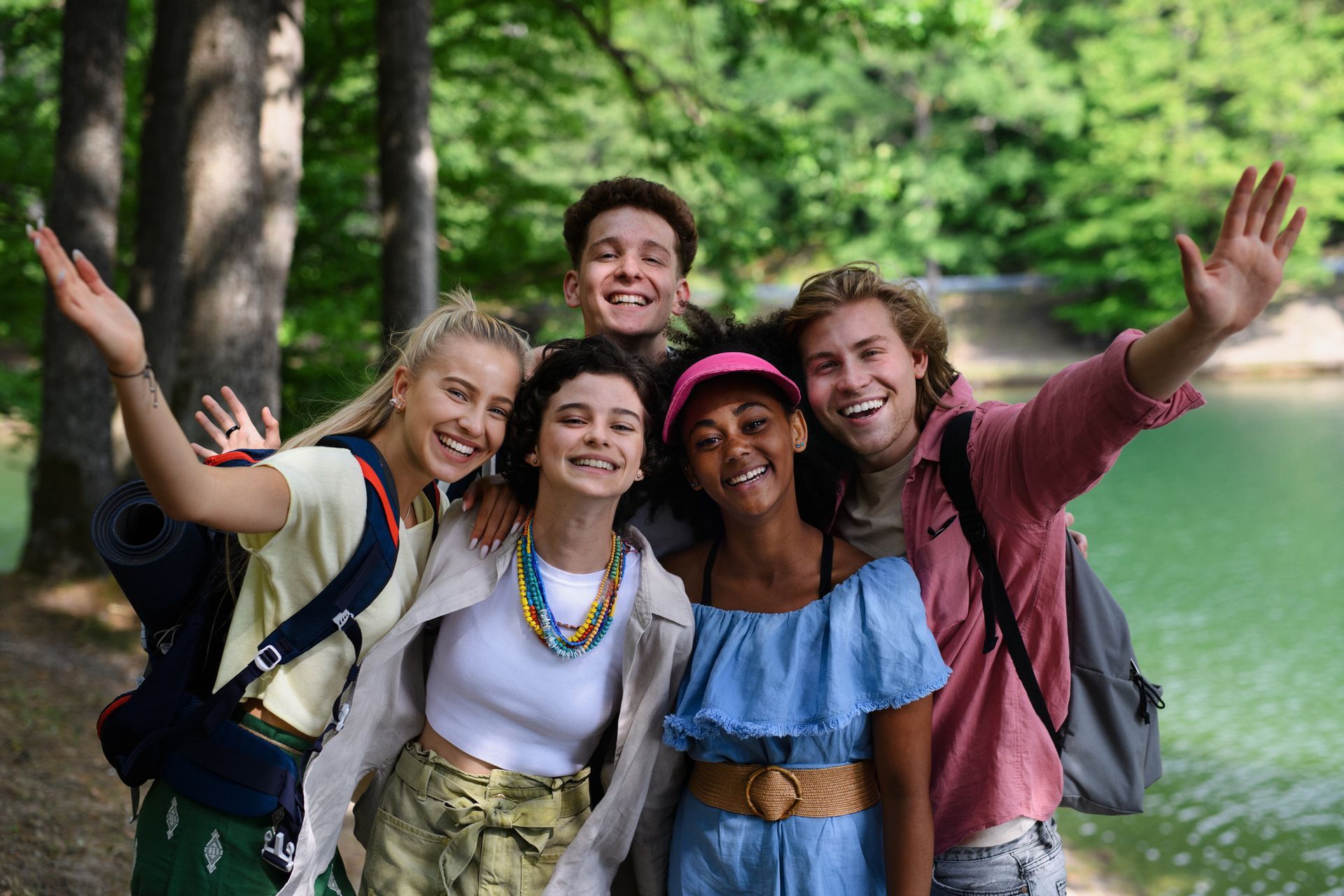 A group of young people are posing for a picture in front of a lake.
