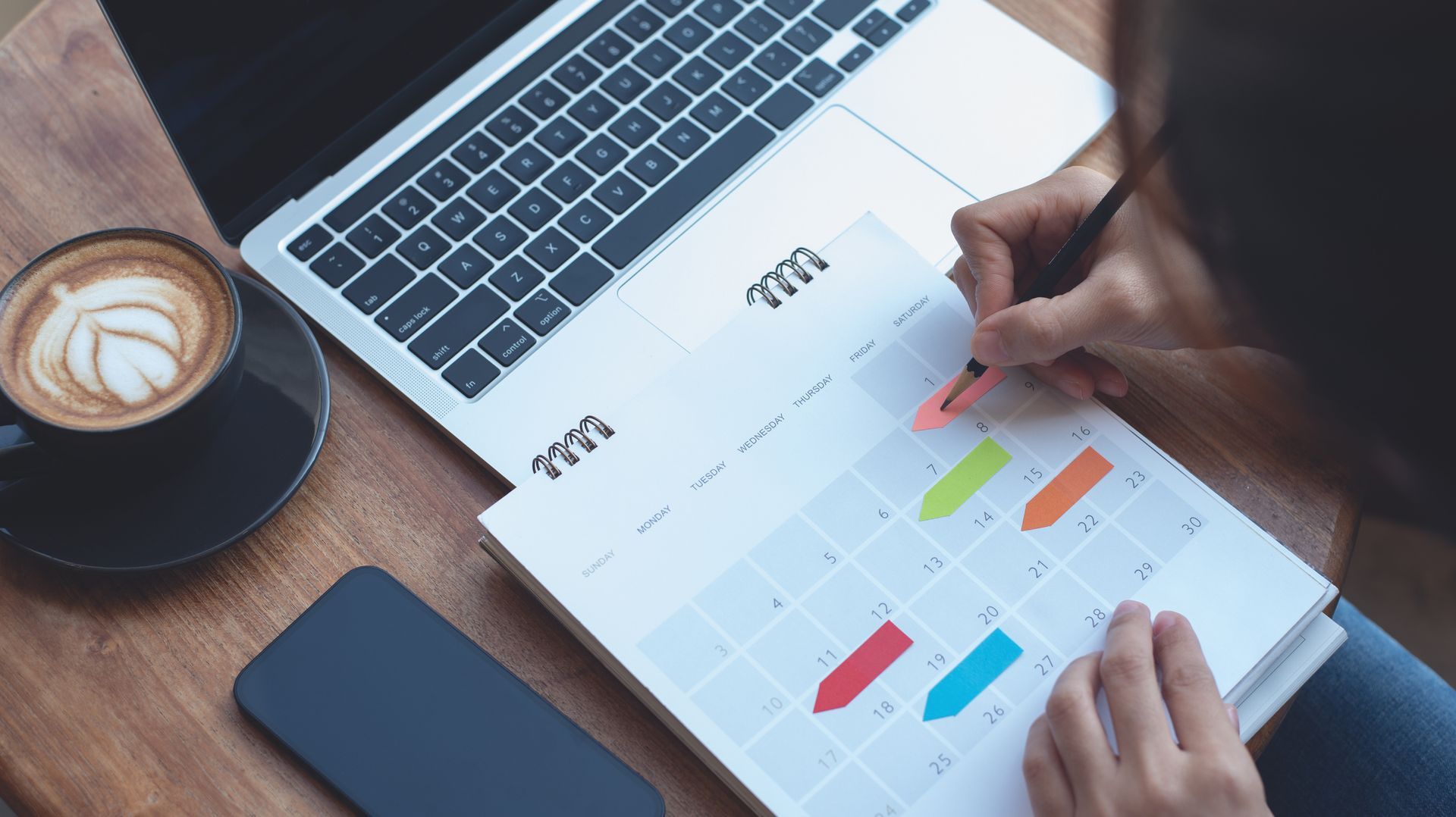 A person is sitting at a table with a laptop and a calendar.