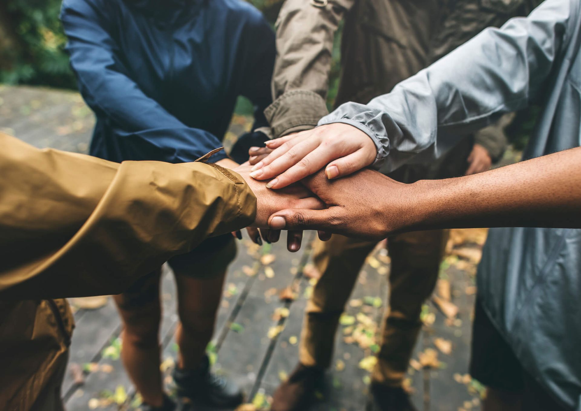 A group of people are putting their hands together in a huddle.