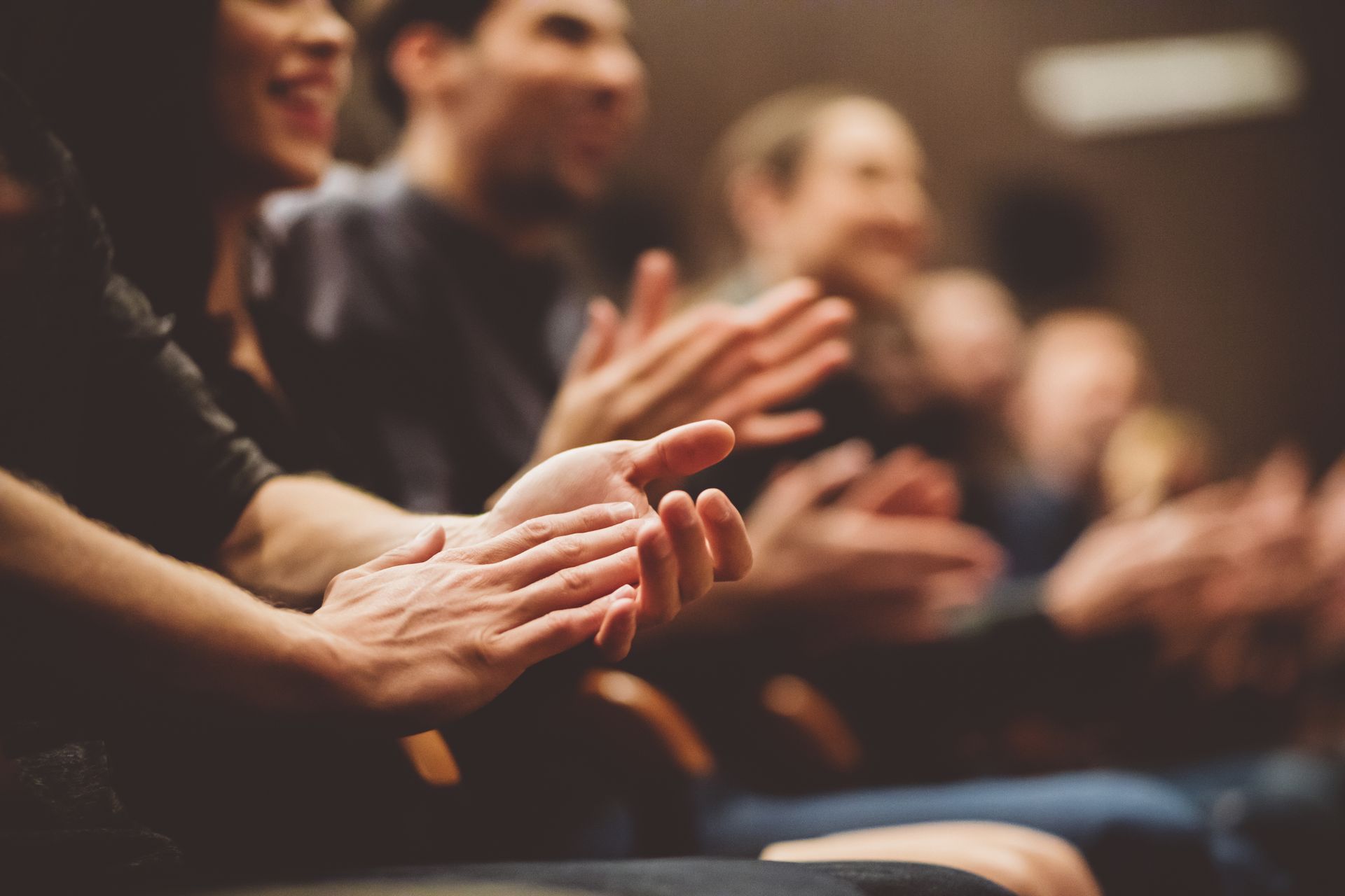 A group of people are clapping their hands in a theater.