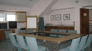 A room with tables and chairs and a white board on the wall