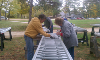 A group of people are working on a metal railing in a park.
