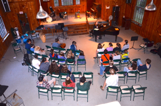 A group of people are sitting in chairs in front of a piano