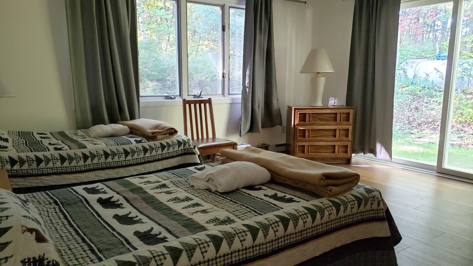 A bedroom with two beds and a sliding glass door.