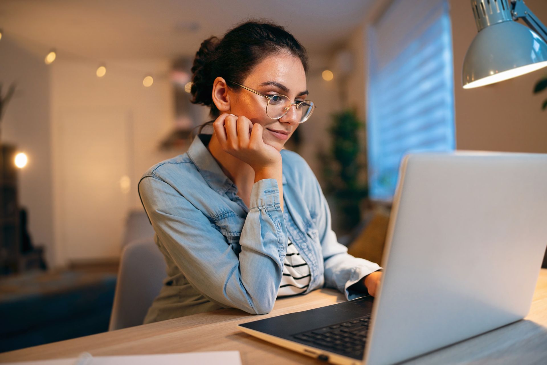 A woman is sitting at a desk using a laptop computer.