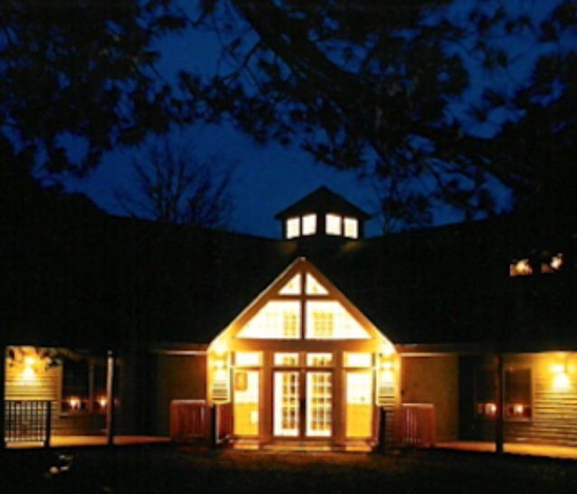 A church is lit up at night with a blue sky in the background