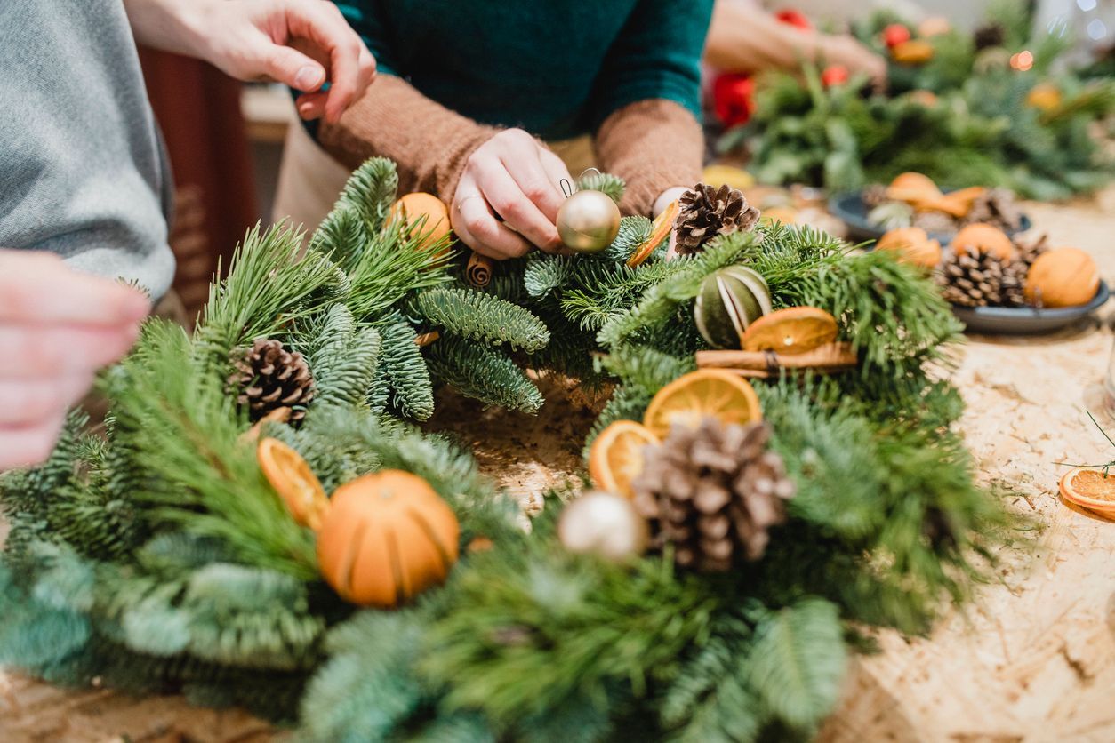 A group of people are making a wreath on a table.