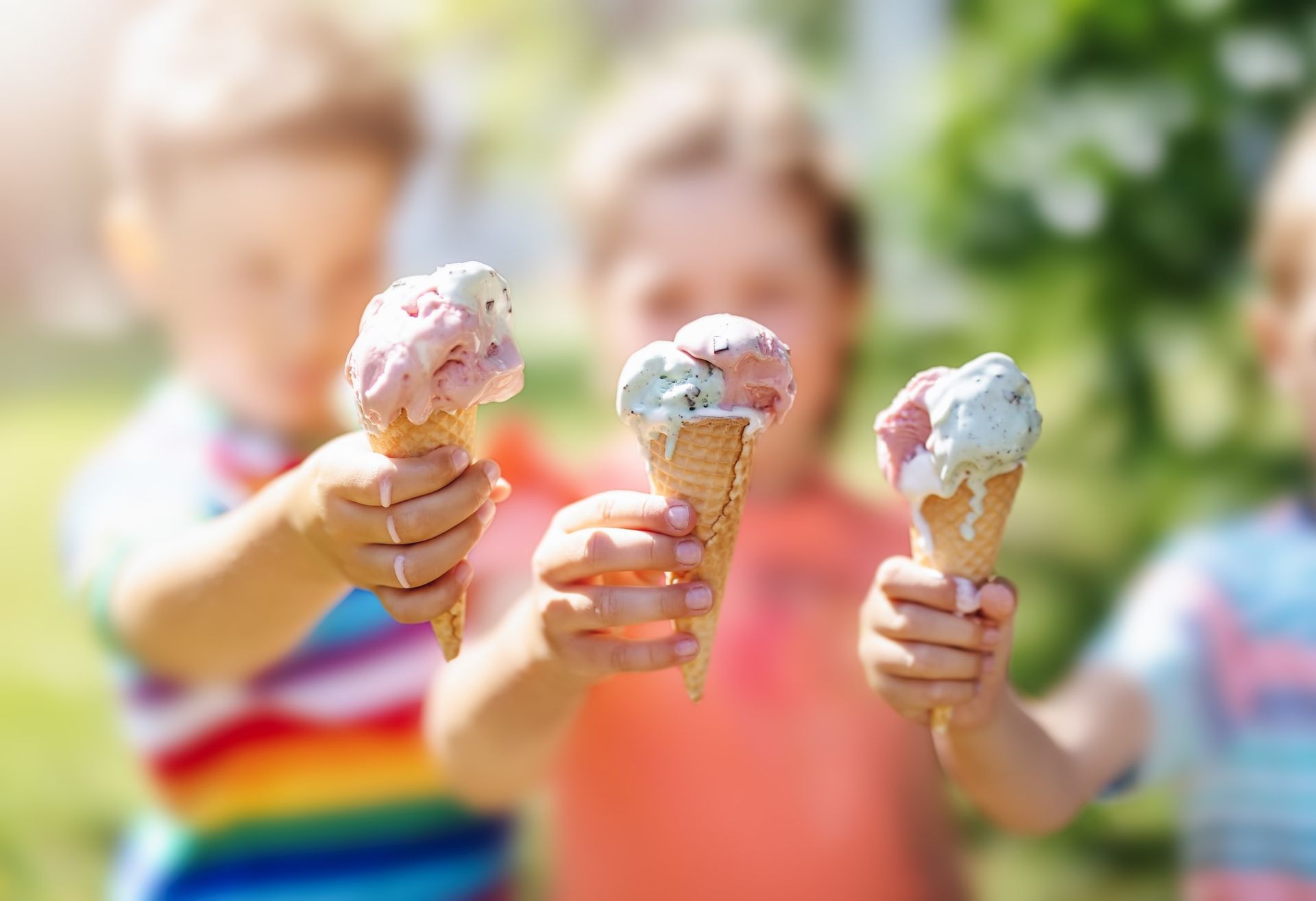 Three children are holding ice cream cones in their hands.