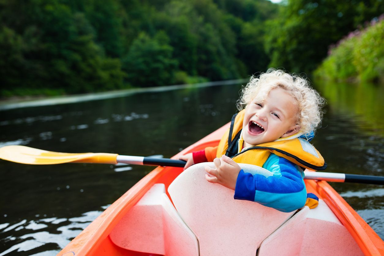 A young boy is rowing a kayak on a river.