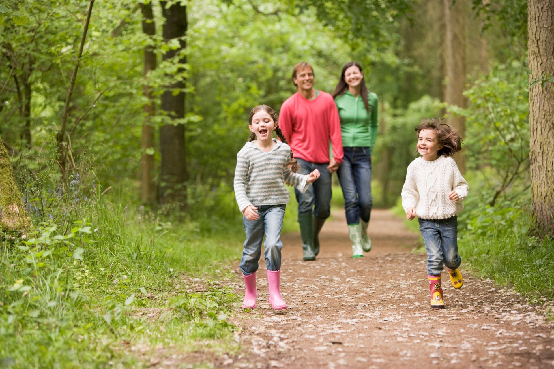 A family is walking down a path in the woods