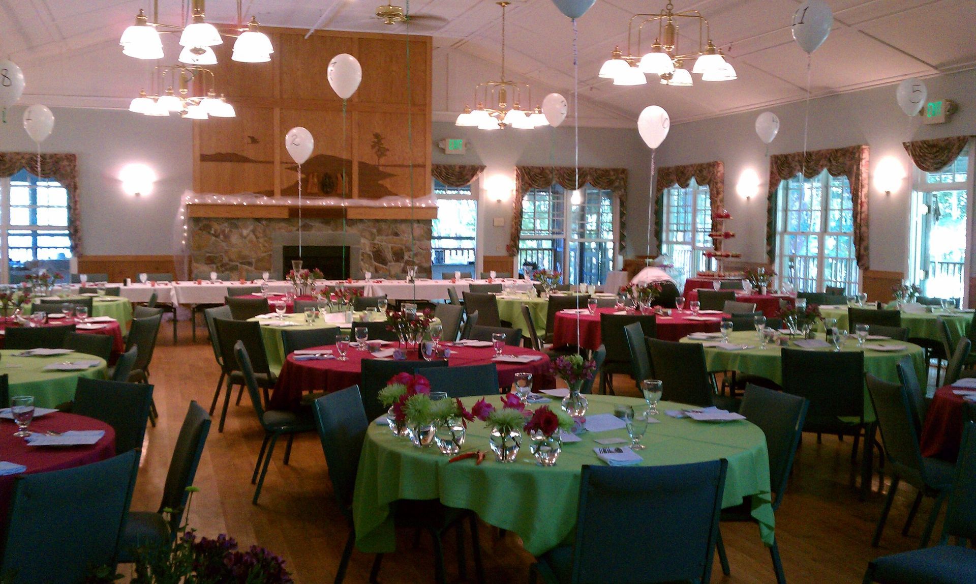 A large room with tables and chairs and balloons hanging from the ceiling