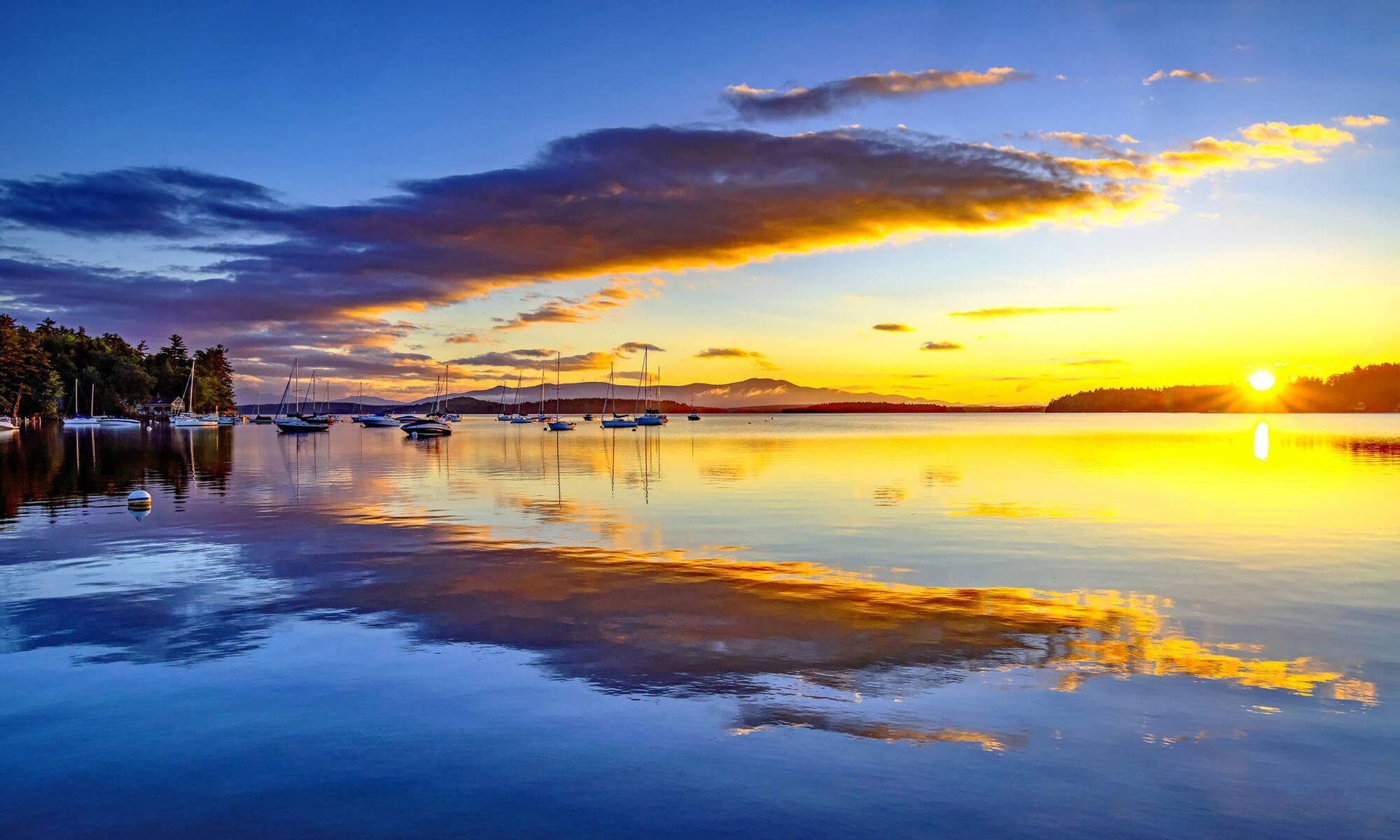 A sunset over Lake Winnipesaukee, NH, with boats in the water.