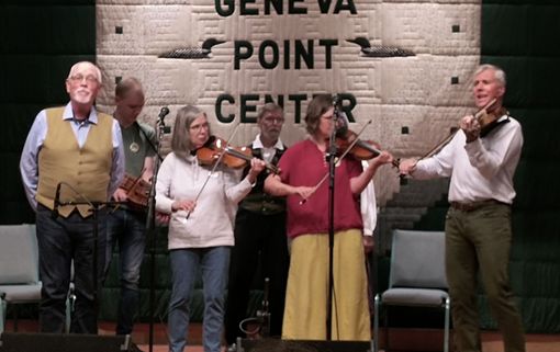 A group of people are playing violins on a stage in front of a sign that says point center.