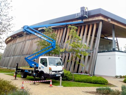 A man is working on a pole with a crane on top of a truck.