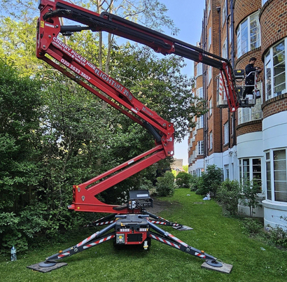 A red crane is sitting in front of a brick building.