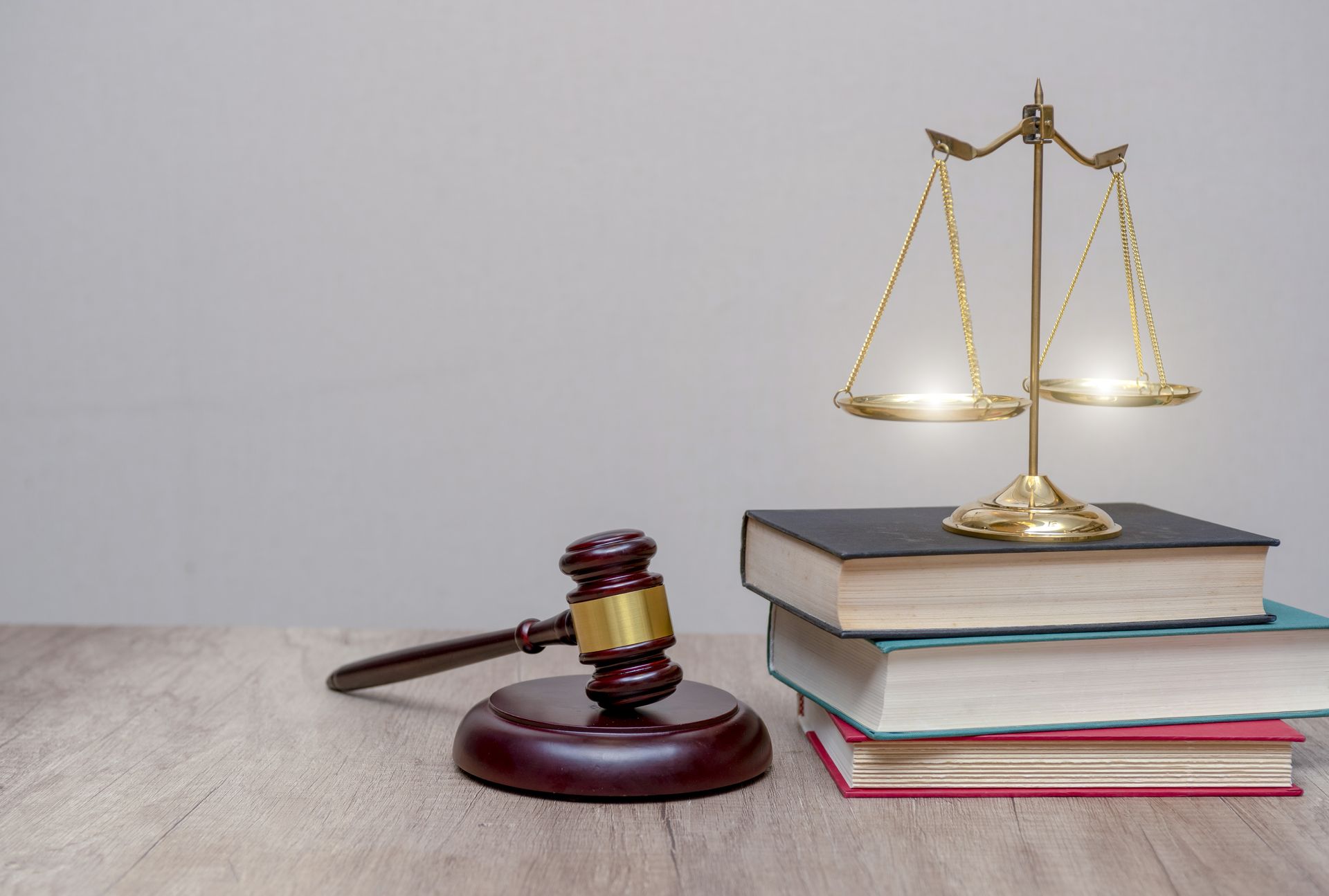 A judge 's gavel , scales of justice , and a stack of books on a wooden table.