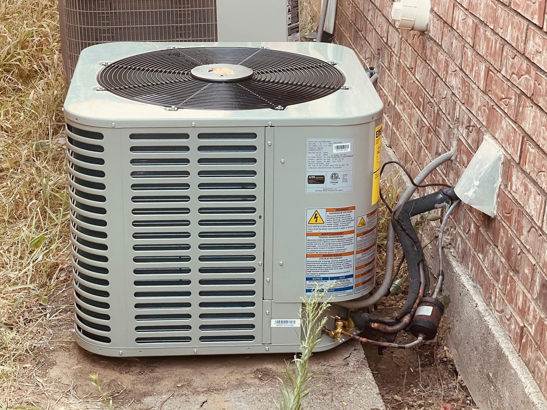 An air conditioner is sitting on the side of a brick building.