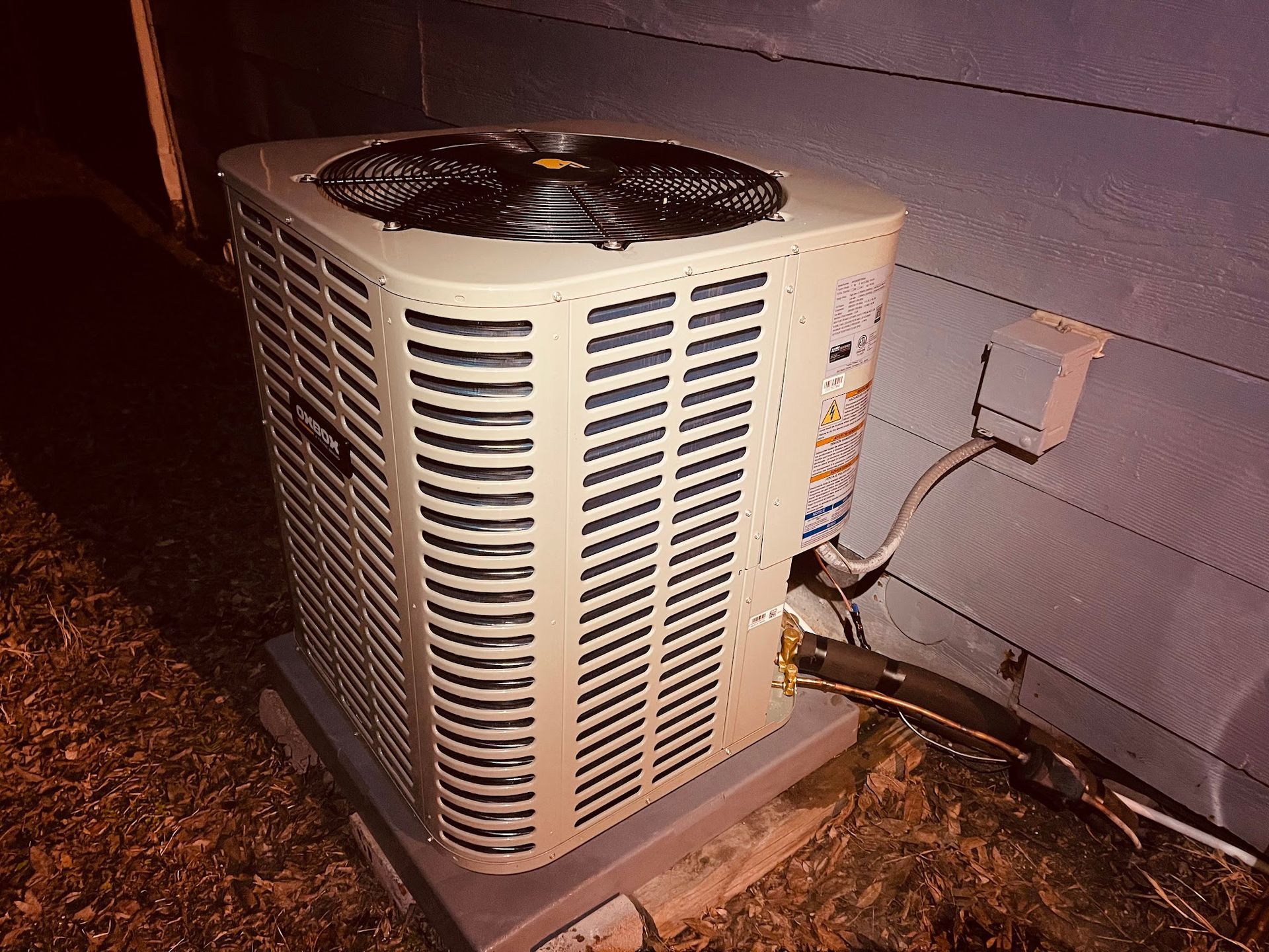 A white air conditioner is sitting outside of a house.
