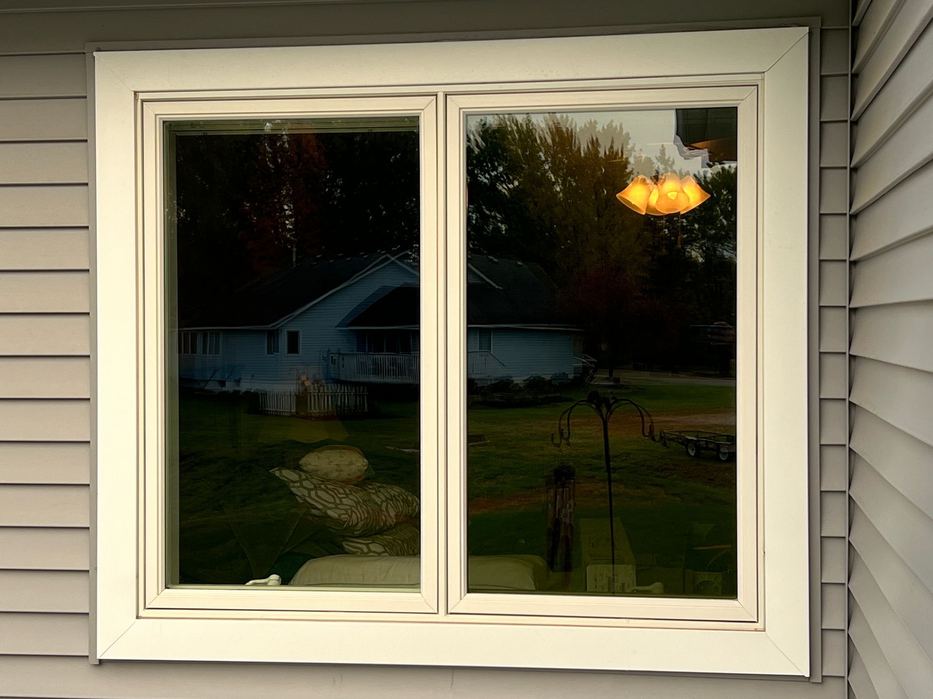 A large window on the side of a house with a reflection of a house in the window.