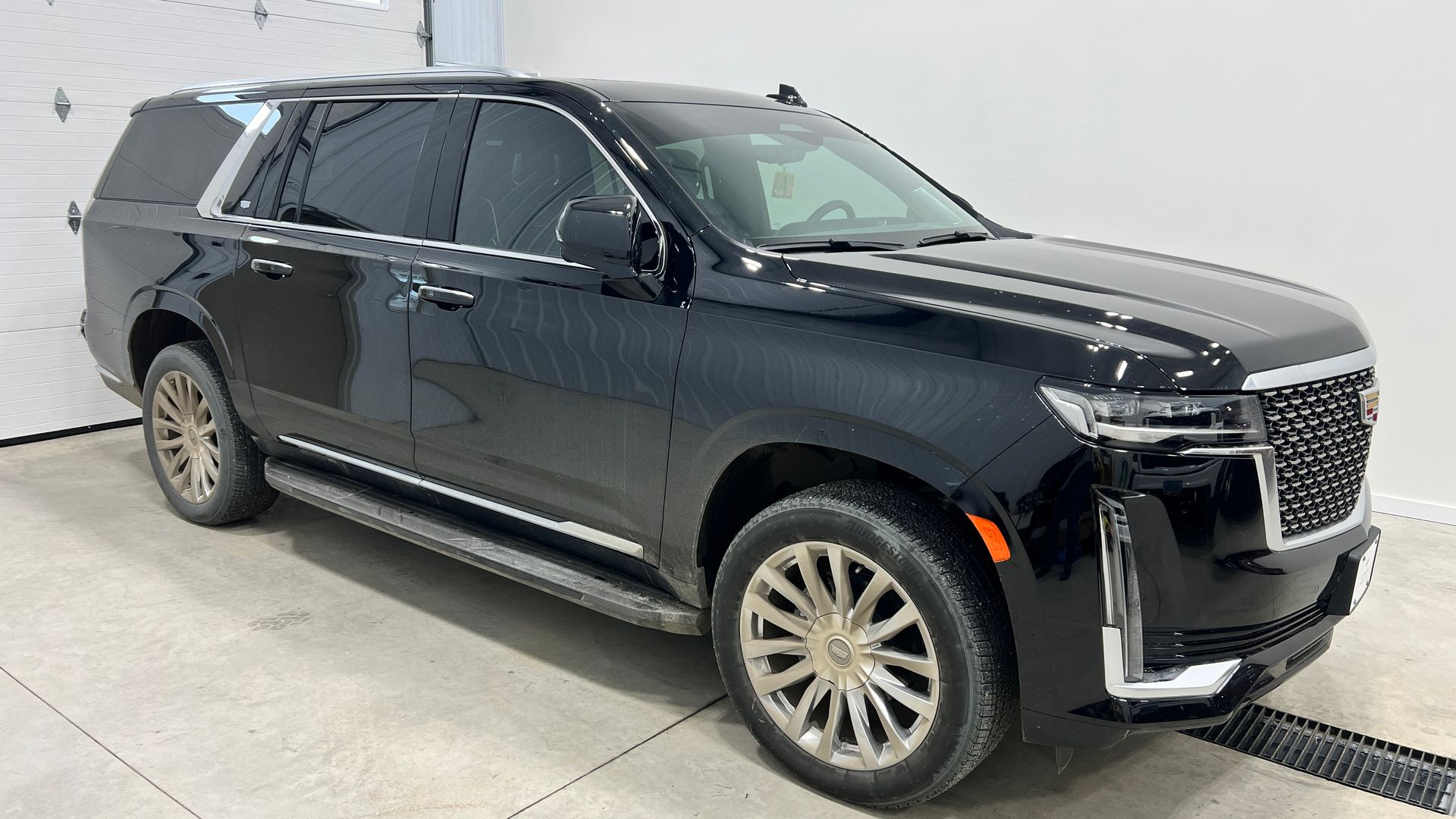 A black gmc yukon is parked in a garage next to a garage door.
