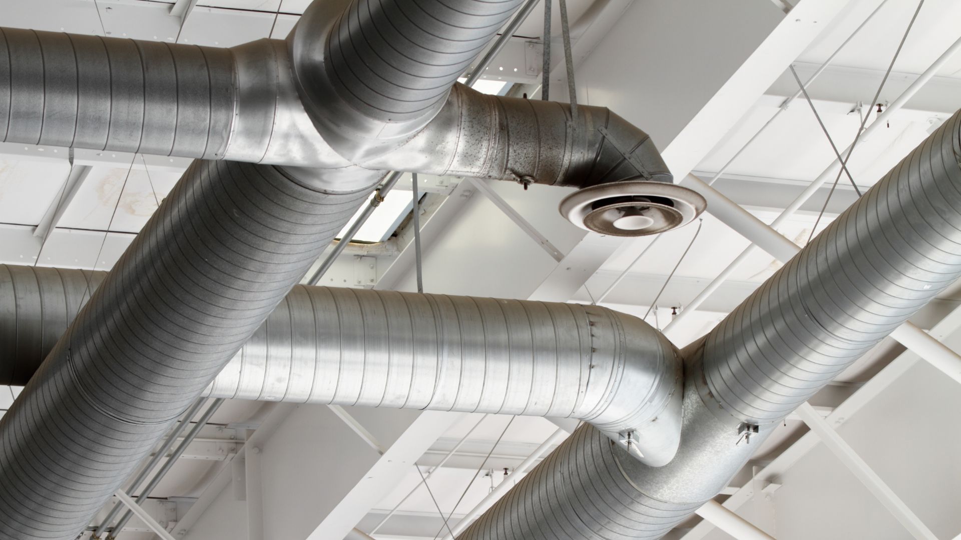 A bunch of metal pipes are hanging from the ceiling of a building.