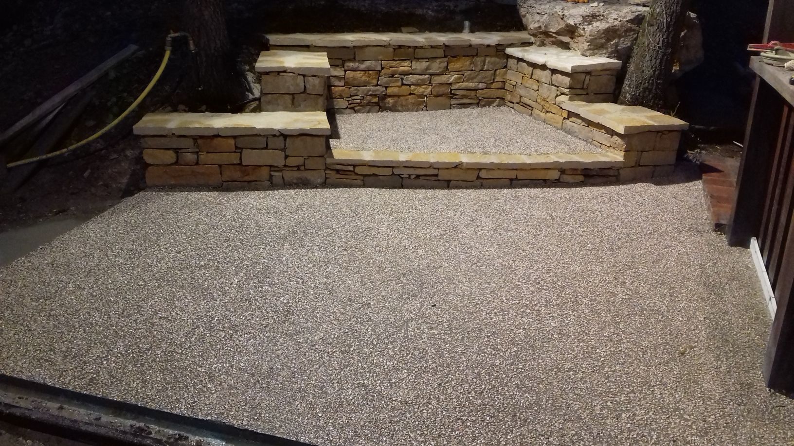 Terrasse en pierre avec marches surélevées et allée de gravier dans un jardin arrière