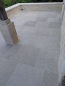 Patio carrelé en pierre avec un muret et une colonne carrée au premier plan