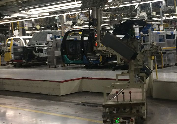 Assembly line with car frames, robot in foreground.