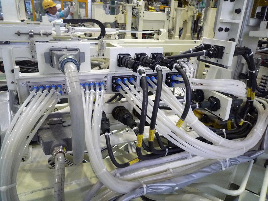 Industrial machinery with numerous cables and connectors, in a factory setting.