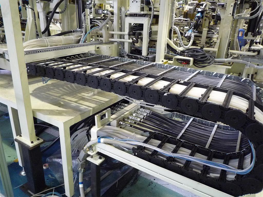 Black cable carrier system on an industrial production line with various cables and wires.